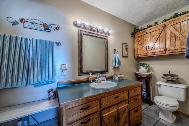 bathroom featuring toilet, vanity, a textured ceiling, and tile patterned floors