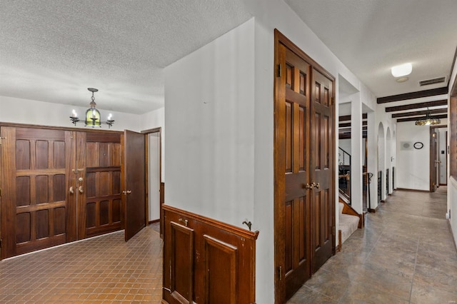 corridor featuring a textured ceiling and an inviting chandelier