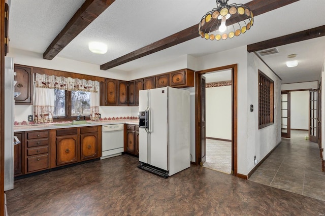 kitchen featuring white appliances, a textured ceiling, and dark brown cabinetry