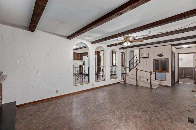 unfurnished living room featuring a textured ceiling, ceiling fan, and beamed ceiling