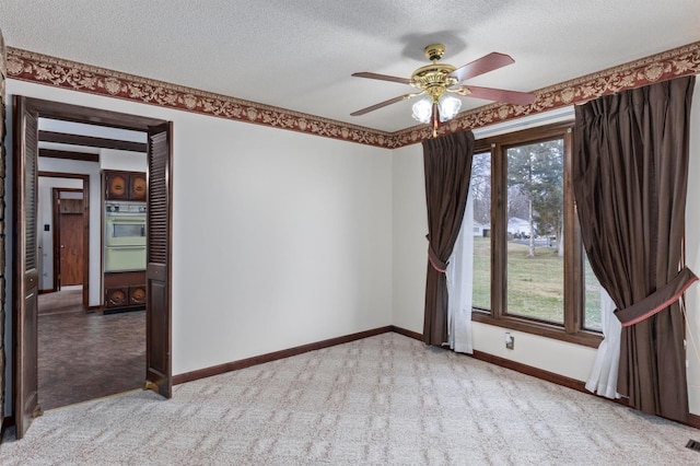 carpeted spare room with a textured ceiling, ceiling fan, and a healthy amount of sunlight