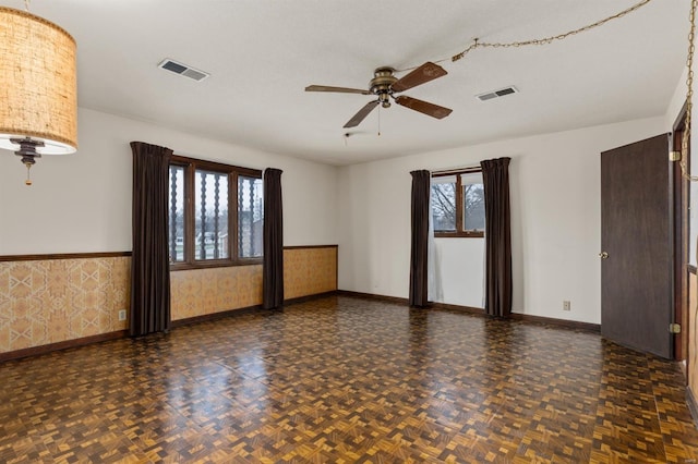 empty room featuring ceiling fan, a wealth of natural light, dark parquet floors, and a textured ceiling