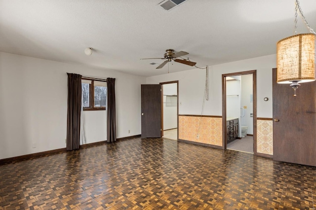 spare room with dark parquet floors, ceiling fan, and a textured ceiling