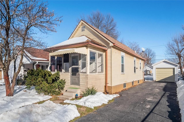 bungalow-style home featuring a sunroom, a garage, and an outbuilding