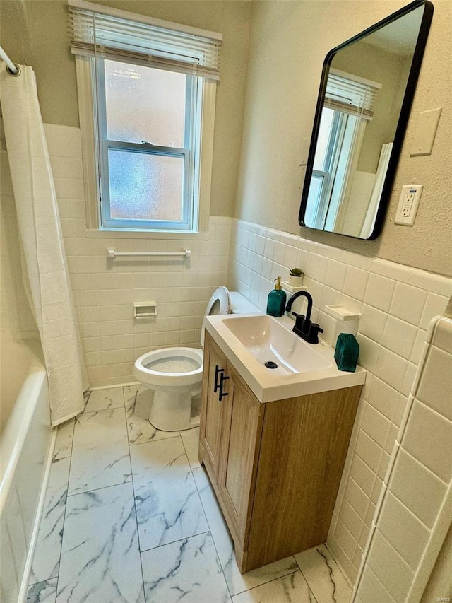 bathroom with vanity, toilet, and tile walls