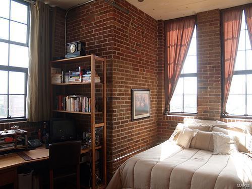 bedroom with multiple windows and brick wall