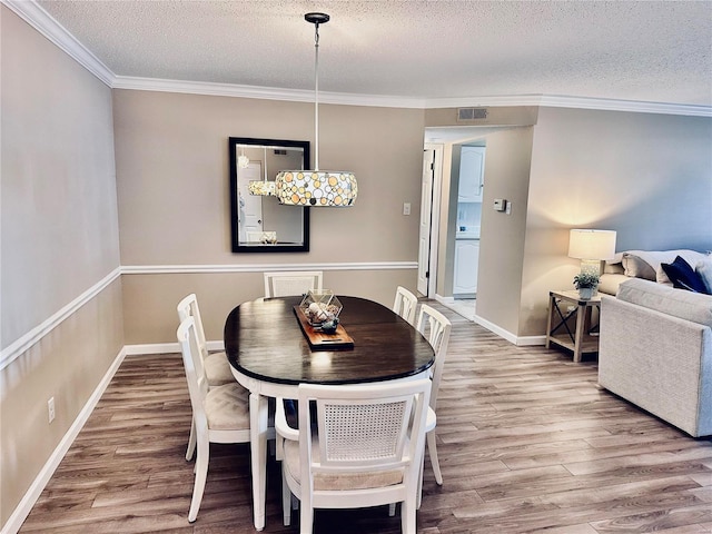 dining room featuring a textured ceiling, crown molding, and wood-type flooring