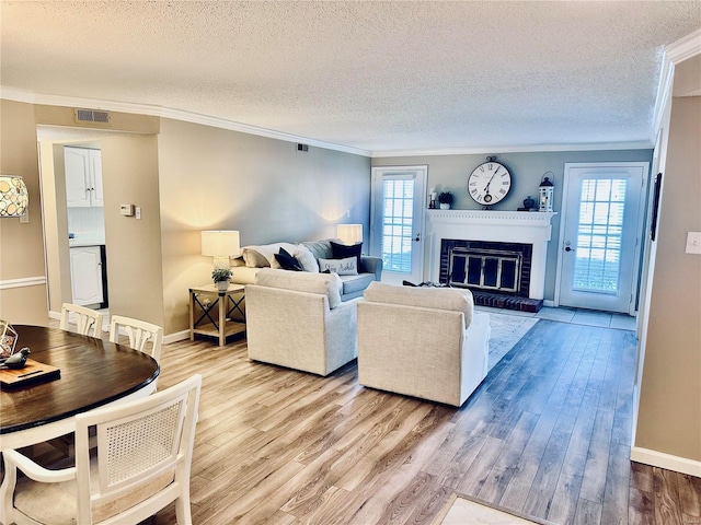 living room with wood-type flooring, a fireplace, ornamental molding, and a healthy amount of sunlight