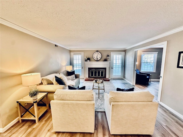 living room featuring a brick fireplace, a textured ceiling, ornamental molding, and hardwood / wood-style flooring