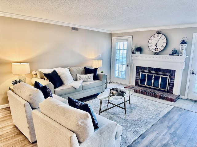 living room featuring a fireplace, a textured ceiling, ornamental molding, and hardwood / wood-style flooring