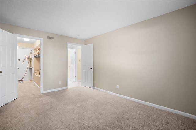 unfurnished bedroom featuring a spacious closet and light carpet