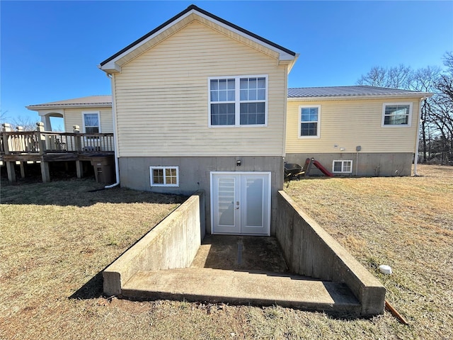 back of property with a wooden deck, a lawn, and french doors