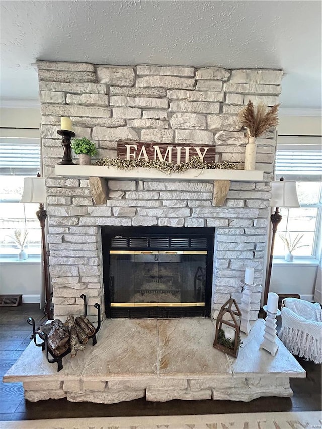 interior details featuring crown molding, a stone fireplace, and a textured ceiling