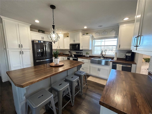 kitchen featuring butcher block counters, sink, white cabinetry, and appliances with stainless steel finishes