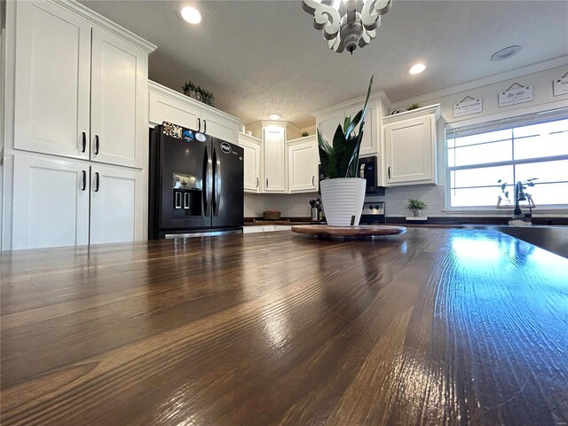 kitchen with white cabinetry, a textured ceiling, and black appliances