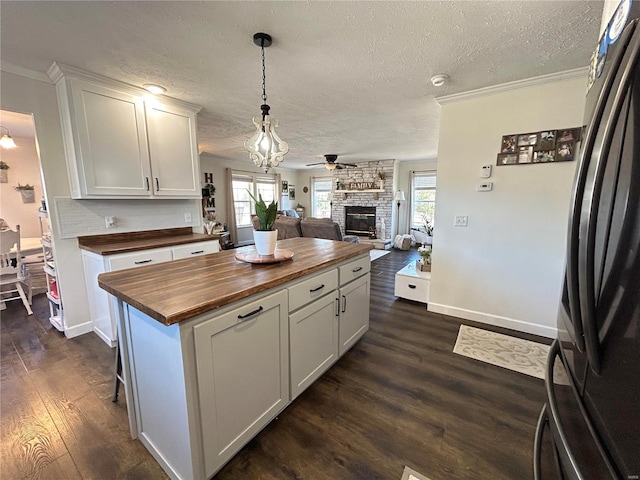 kitchen featuring butcher block counters, black refrigerator, white cabinets, and a kitchen island