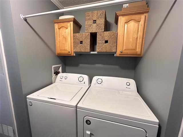 clothes washing area featuring independent washer and dryer and cabinets