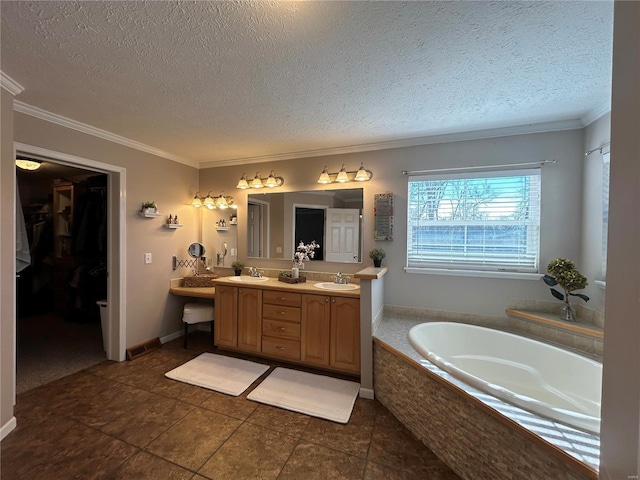 bathroom with tile patterned flooring, vanity, tiled tub, crown molding, and a textured ceiling