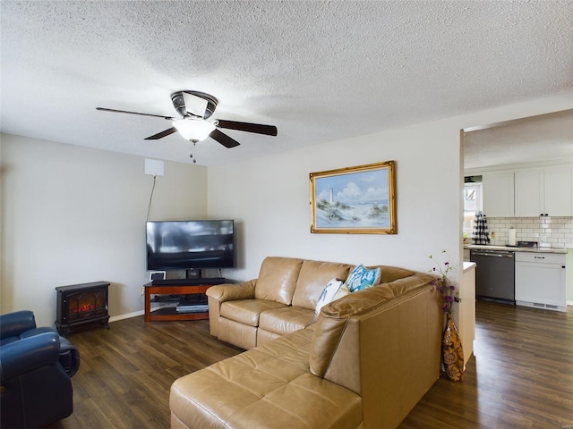 living room with ceiling fan, dark hardwood / wood-style flooring, a wood stove, and a textured ceiling