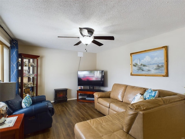 living room with ceiling fan, a wood stove, a textured ceiling, and dark hardwood / wood-style flooring