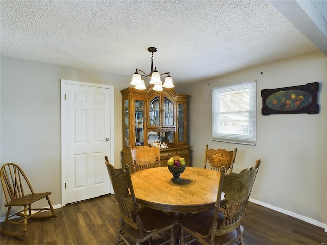 dining area featuring dark wood-type flooring, a textured ceiling, and an inviting chandelier