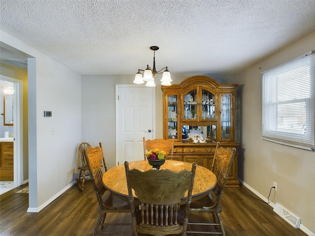 dining room with dark hardwood / wood-style flooring, a chandelier, and a textured ceiling