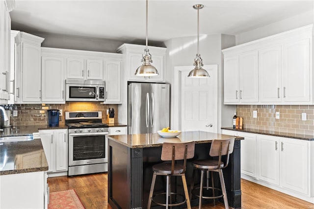 kitchen featuring stainless steel appliances, white cabinets, a center island, and sink