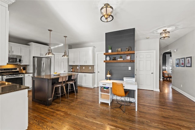 kitchen featuring appliances with stainless steel finishes, white cabinetry, a center island, and tasteful backsplash