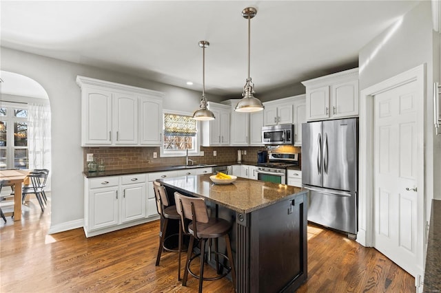 kitchen featuring appliances with stainless steel finishes, a center island, decorative backsplash, white cabinets, and sink