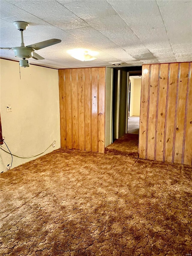 basement featuring wooden walls and dark colored carpet