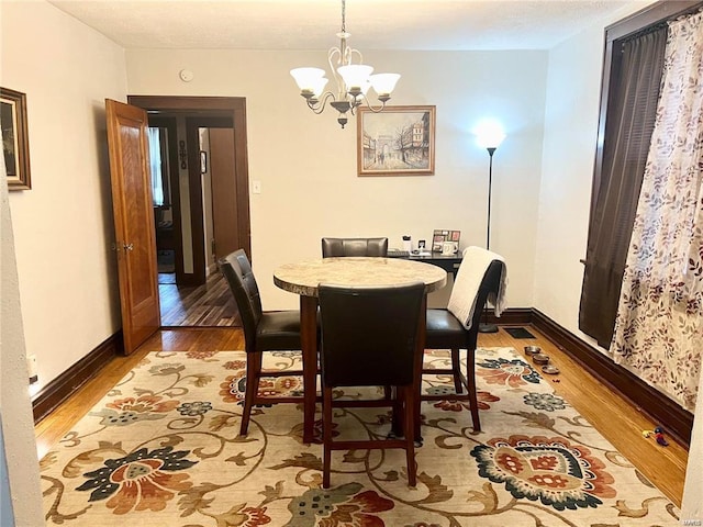 dining area featuring wood-type flooring and a chandelier