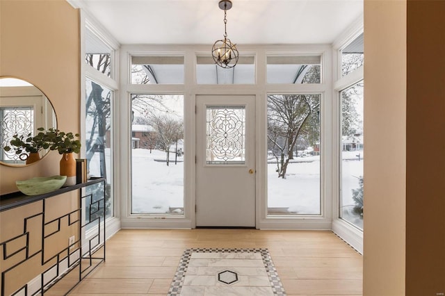 doorway to outside featuring a wall of windows, light hardwood / wood-style floors, and a notable chandelier