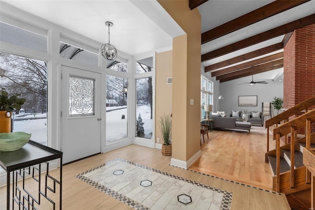 entrance foyer with ceiling fan with notable chandelier, light hardwood / wood-style floors, and beam ceiling