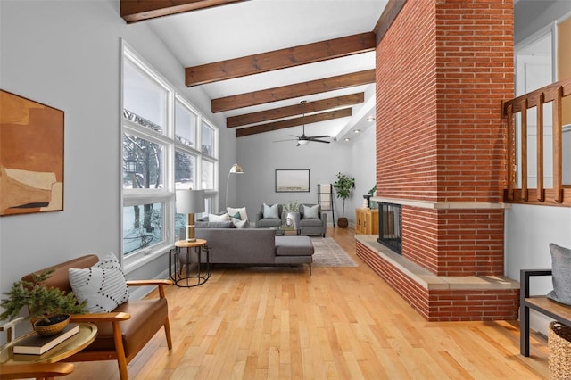 living room with a fireplace, light wood-type flooring, ceiling fan, high vaulted ceiling, and beam ceiling