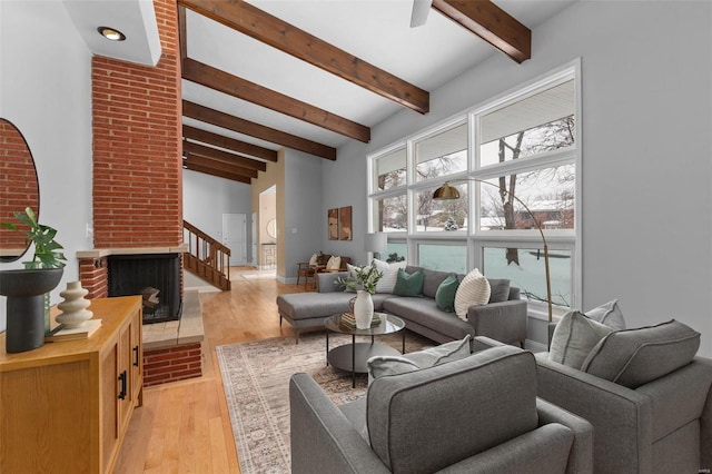 living room featuring a fireplace, light wood-type flooring, and beam ceiling