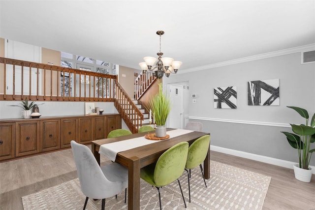 dining space with light hardwood / wood-style floors, an inviting chandelier, and ornamental molding