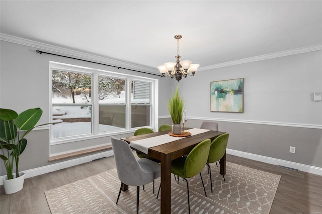 dining room featuring ornamental molding, an inviting chandelier, and hardwood / wood-style flooring