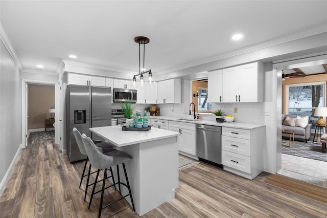 kitchen with stainless steel appliances, a center island, white cabinetry, decorative light fixtures, and tasteful backsplash