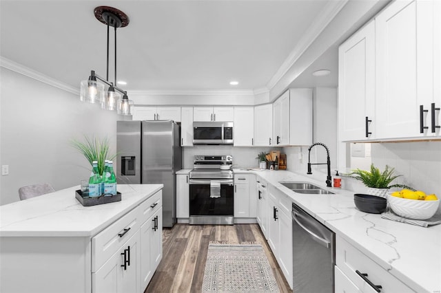 kitchen featuring light stone counters, pendant lighting, stainless steel appliances, white cabinetry, and sink