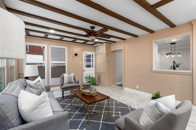 living room with brick wall, ceiling fan, and beamed ceiling