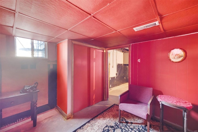 living area featuring a drop ceiling and concrete flooring