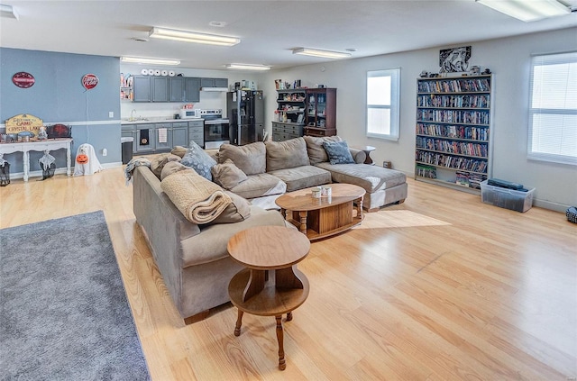 living room featuring a healthy amount of sunlight, sink, and light hardwood / wood-style flooring