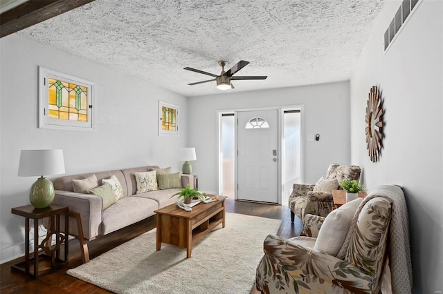 living room featuring a textured ceiling, dark hardwood / wood-style floors, and ceiling fan