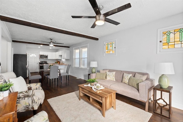 living room with ceiling fan, dark wood-type flooring, a textured ceiling, and beamed ceiling