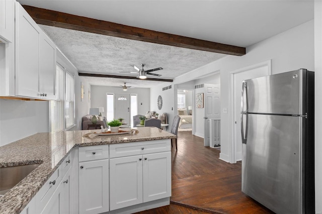 kitchen with white cabinets, stainless steel fridge, dark hardwood / wood-style floors, kitchen peninsula, and light stone counters