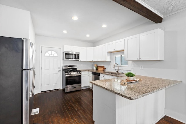 kitchen with kitchen peninsula, sink, white cabinets, beamed ceiling, and stainless steel appliances