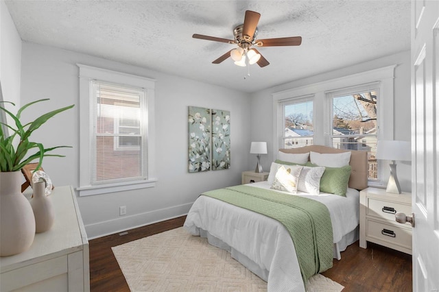 bedroom featuring ceiling fan, dark hardwood / wood-style floors, a textured ceiling, and multiple windows