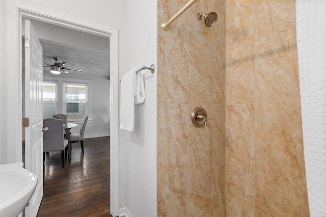 bathroom with ceiling fan, hardwood / wood-style floors, a tile shower, and a textured ceiling