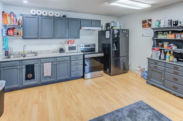 kitchen featuring sink, light hardwood / wood-style floors, black fridge, and stainless steel range with electric cooktop