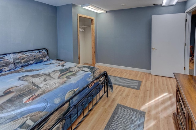 bedroom with a closet, baseboards, and light wood finished floors